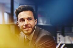 Young business man in an office. Primary colors: blue and yellow.