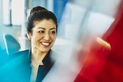 Woman in suit smiling. Japan. Primary color: red.